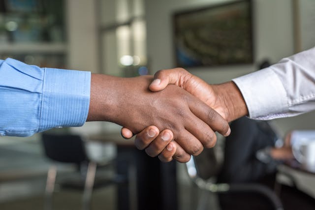 two people in dress shirts shaking hands